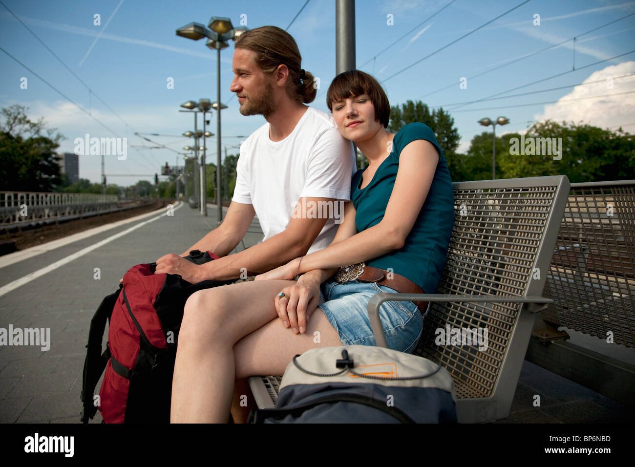 Un annoiato backpacker matura in attesa del loro treno su una piattaforma del treno Foto Stock