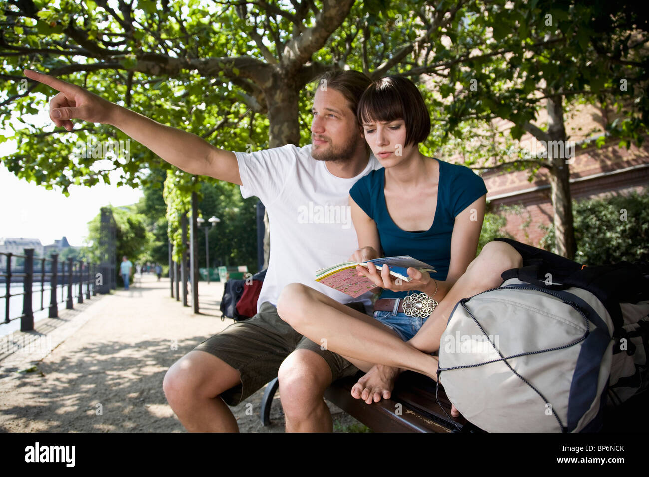Un giovane uomo di punta, mentre la sua ragazza guarda una mappa con incertezza Foto Stock