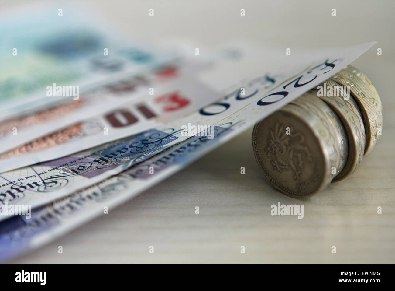 Denominazione diversa sterling note in appoggio su £1 monete Foto Stock