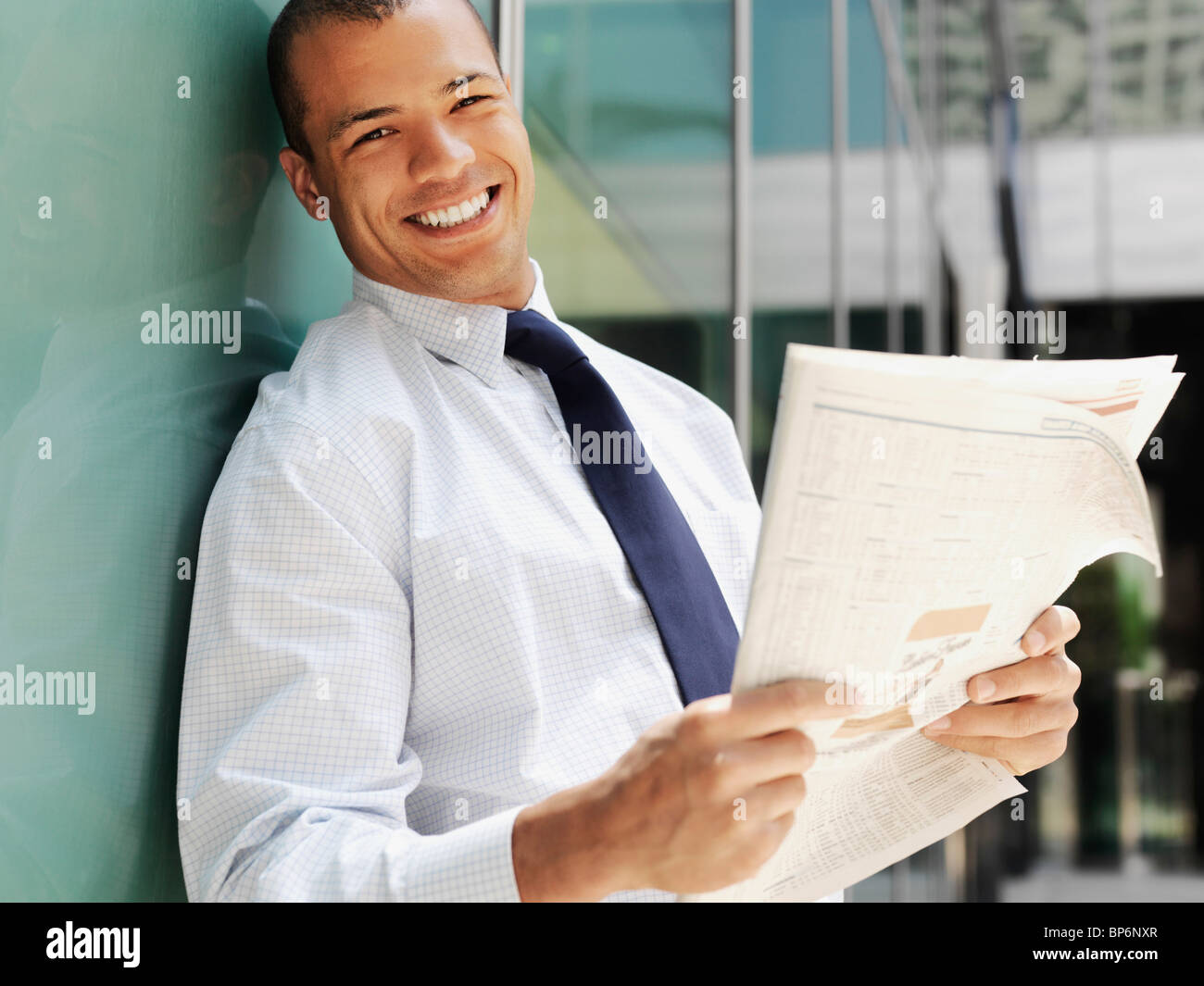 Imprenditore sorridente tenendo un giornale Foto Stock