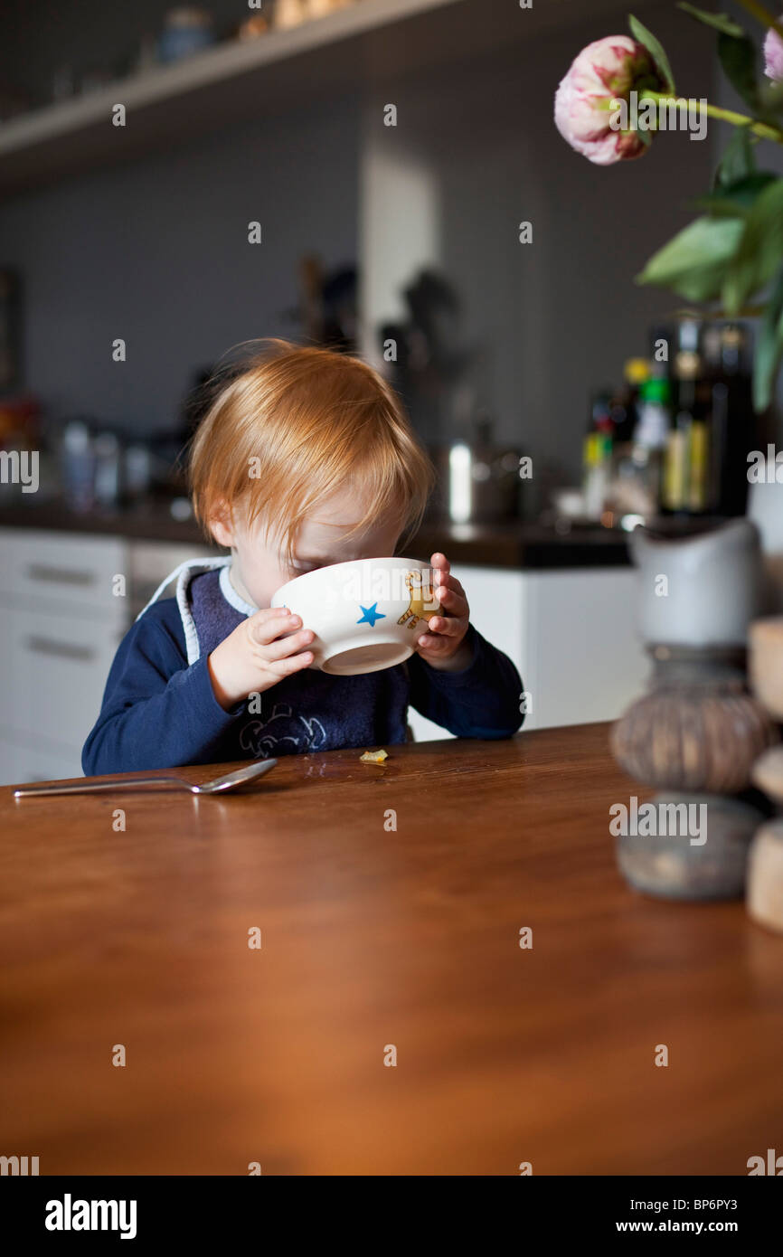 Un giovane ragazzo di mangiare da una ciotola Foto Stock