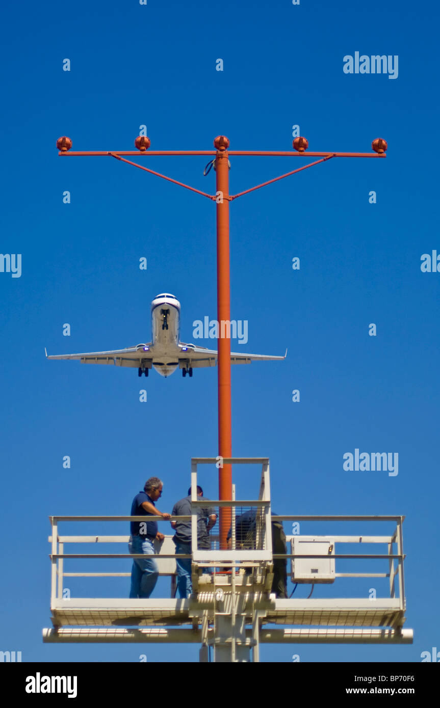 La gente che lavora sulla pista approccio luci sotto il jet aereo in atterraggio a Los Angeles Int'l Airport LAX, California Foto Stock