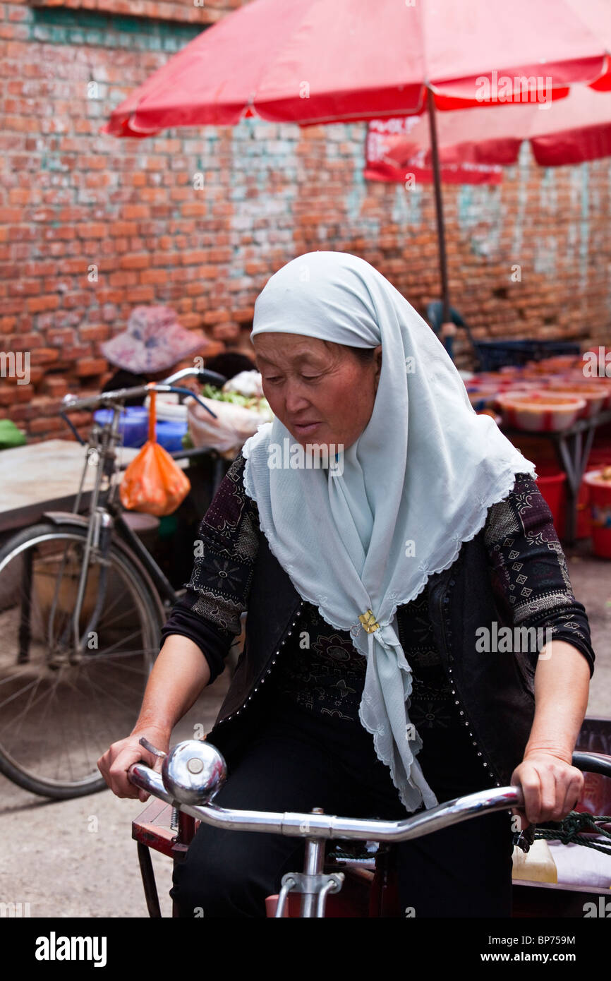 Musulmani donna cinese in sella ad una bicicletta nel villaggio Xizhou, appena fuori Dali, Cina Foto Stock