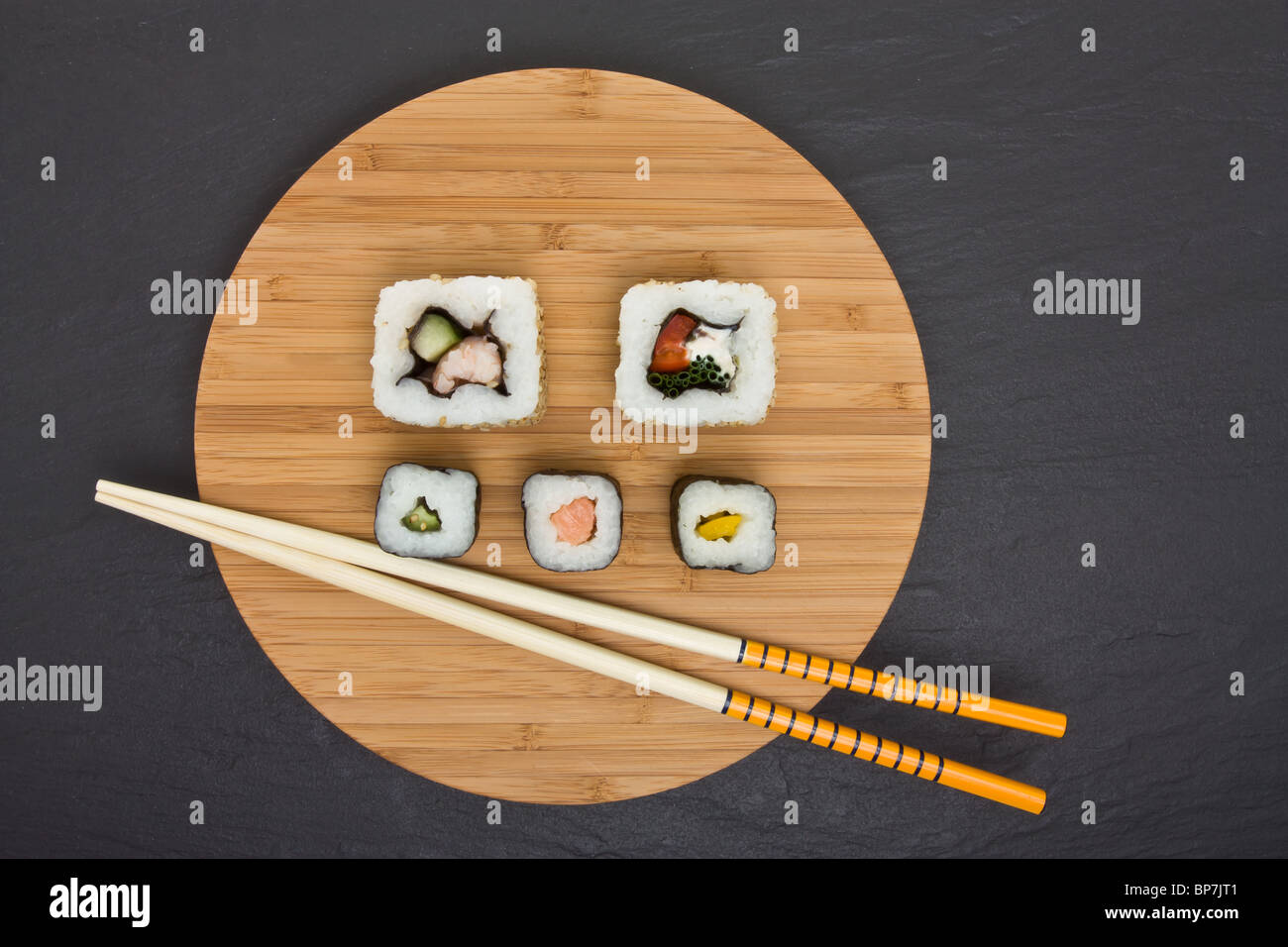 Il Sushi e scheda di bambù con bacchette sul grigio scuro dello sfondo in ardesia. Foto Stock