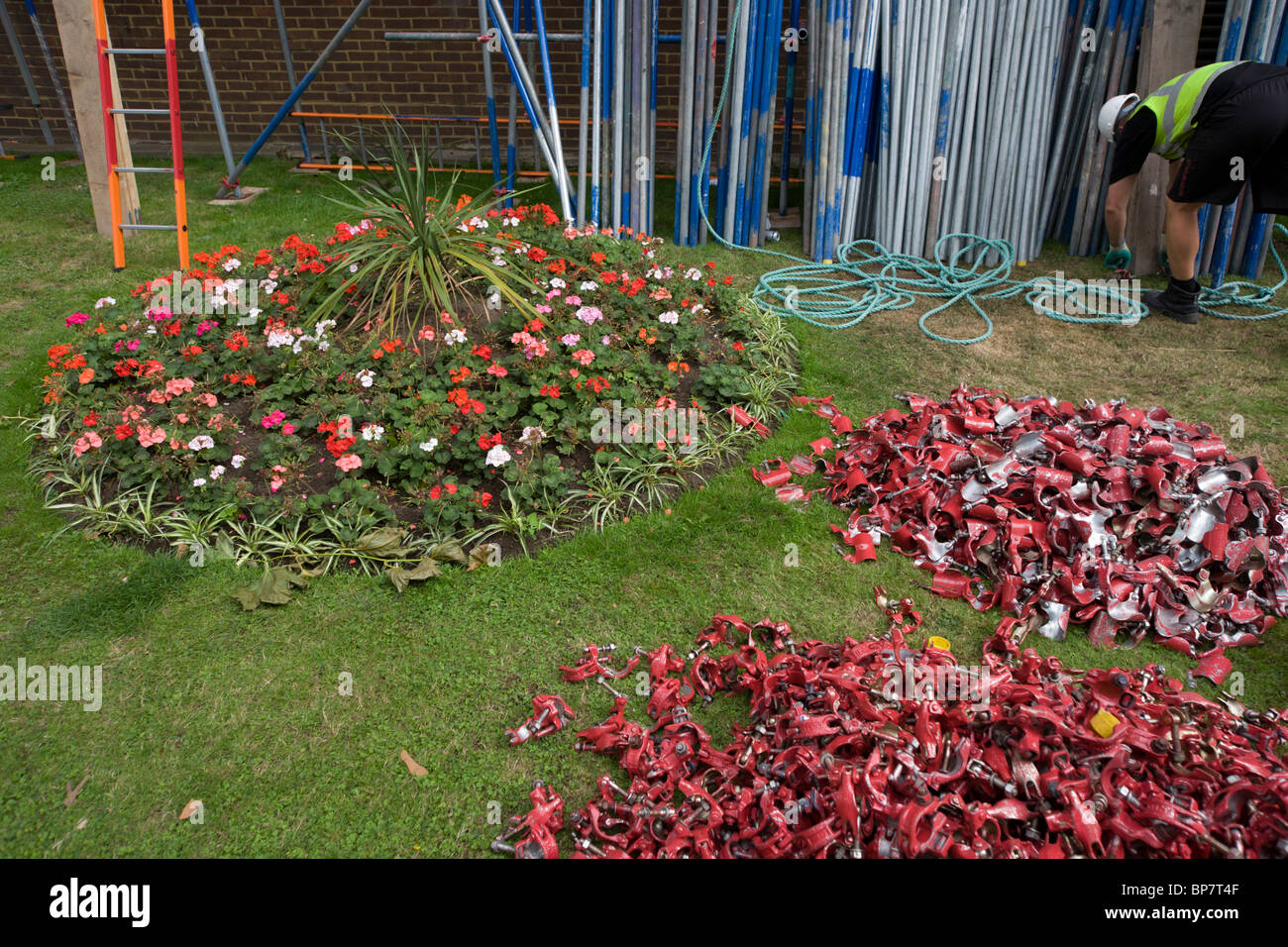 Ponteggio attrezzature e letto di fiori durante i lavori di ristrutturazione a un blocco di appartamenti in proprietà del giardino. Foto Stock