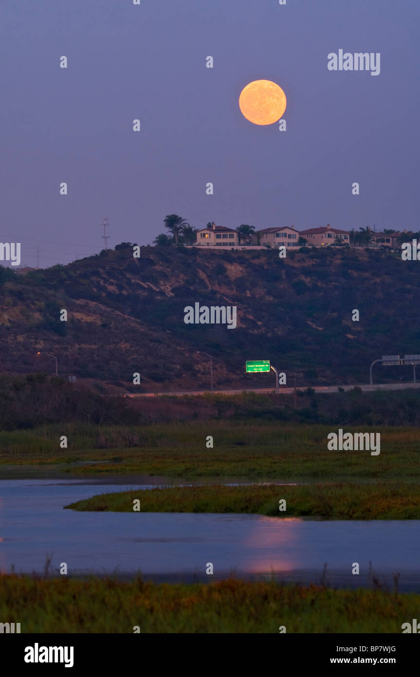 Full Moon Rising nella luce della sera su case e di estuario, Los Penasquitos Marsh Riserva Naturale, San Diego, California Foto Stock