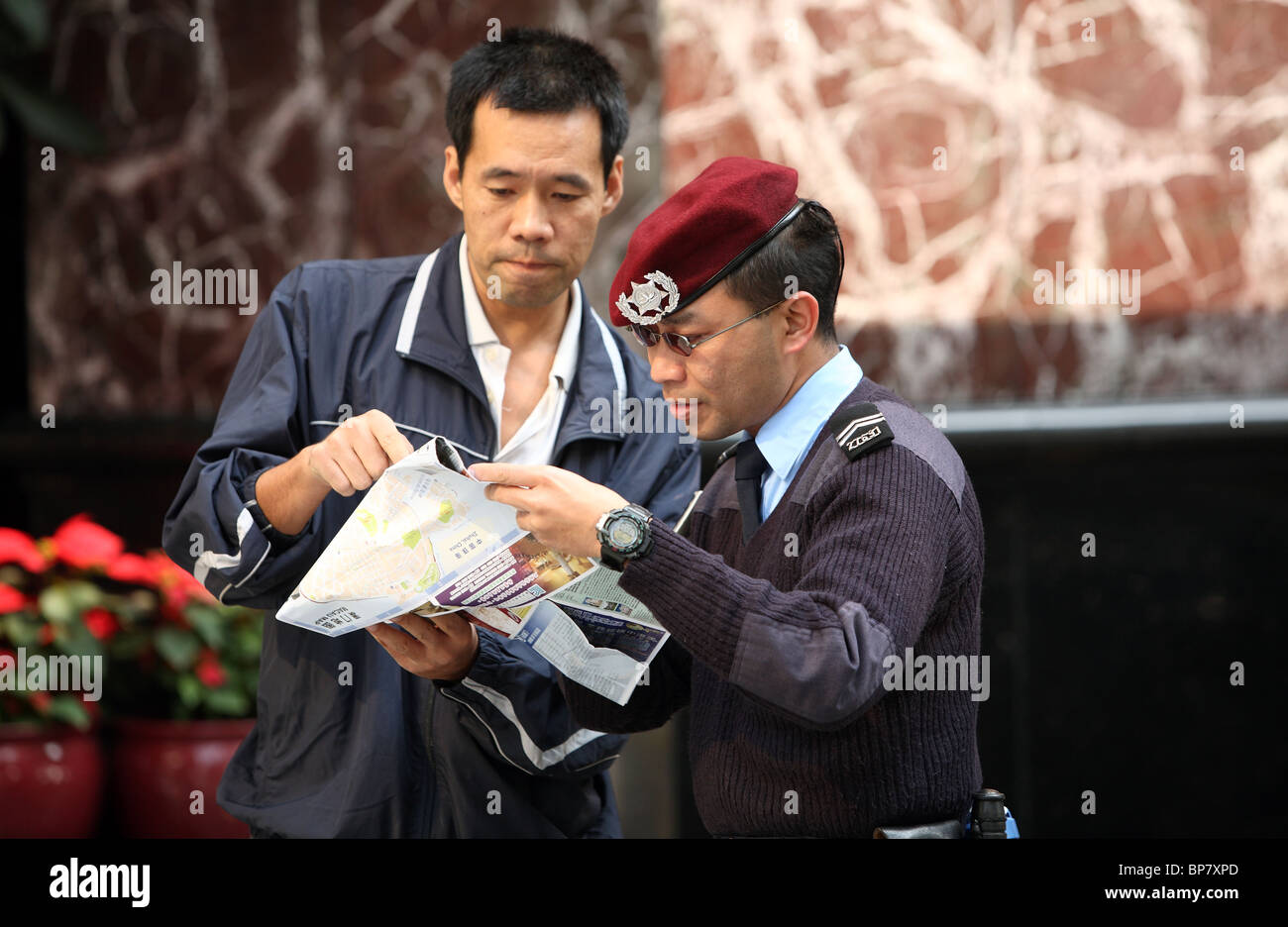Poliziotto che mostra un uomo la strada sulla mappa della città, Macao, Cina Foto Stock