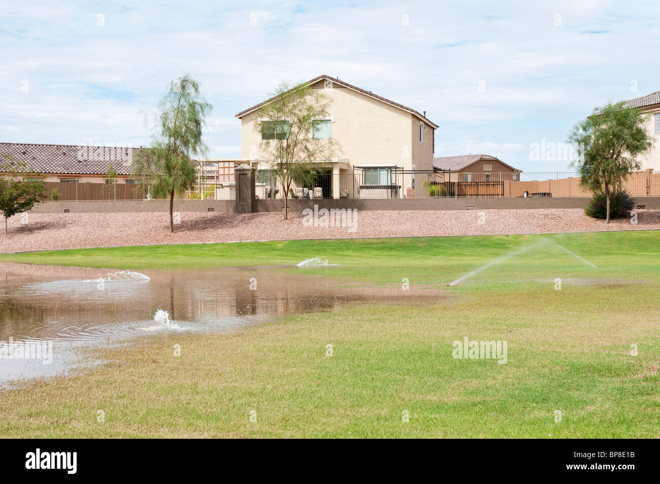Un paesaggio automatico sistema di irrigazione spruzza acqua in un bacino dove acqua di temporale è stato raccolto dopo una pesante pioggia tempesta. Foto Stock