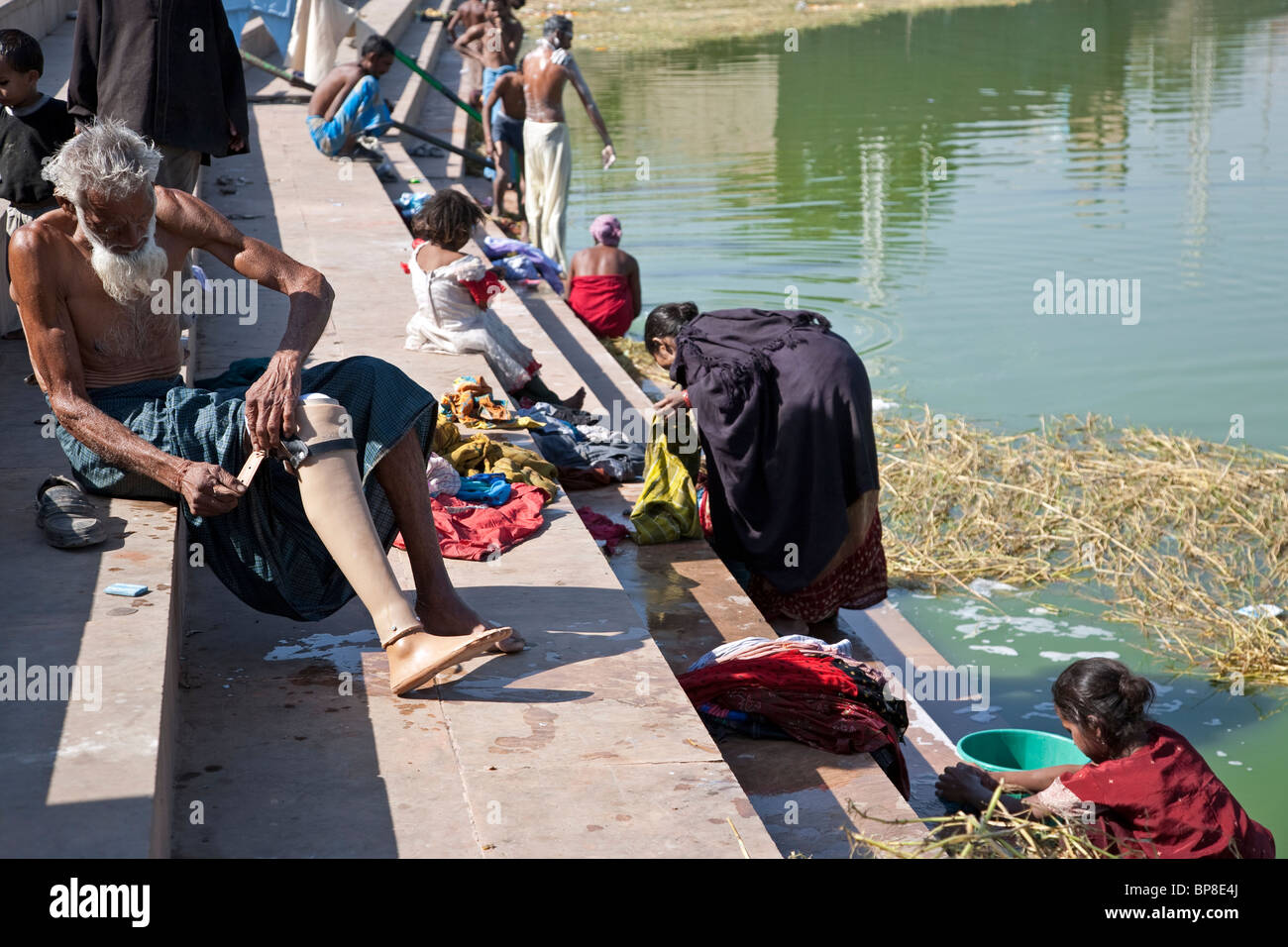 L'uomo mettendo su una gamba protesica. Gange fiume ghats. Varanasi. India Foto Stock