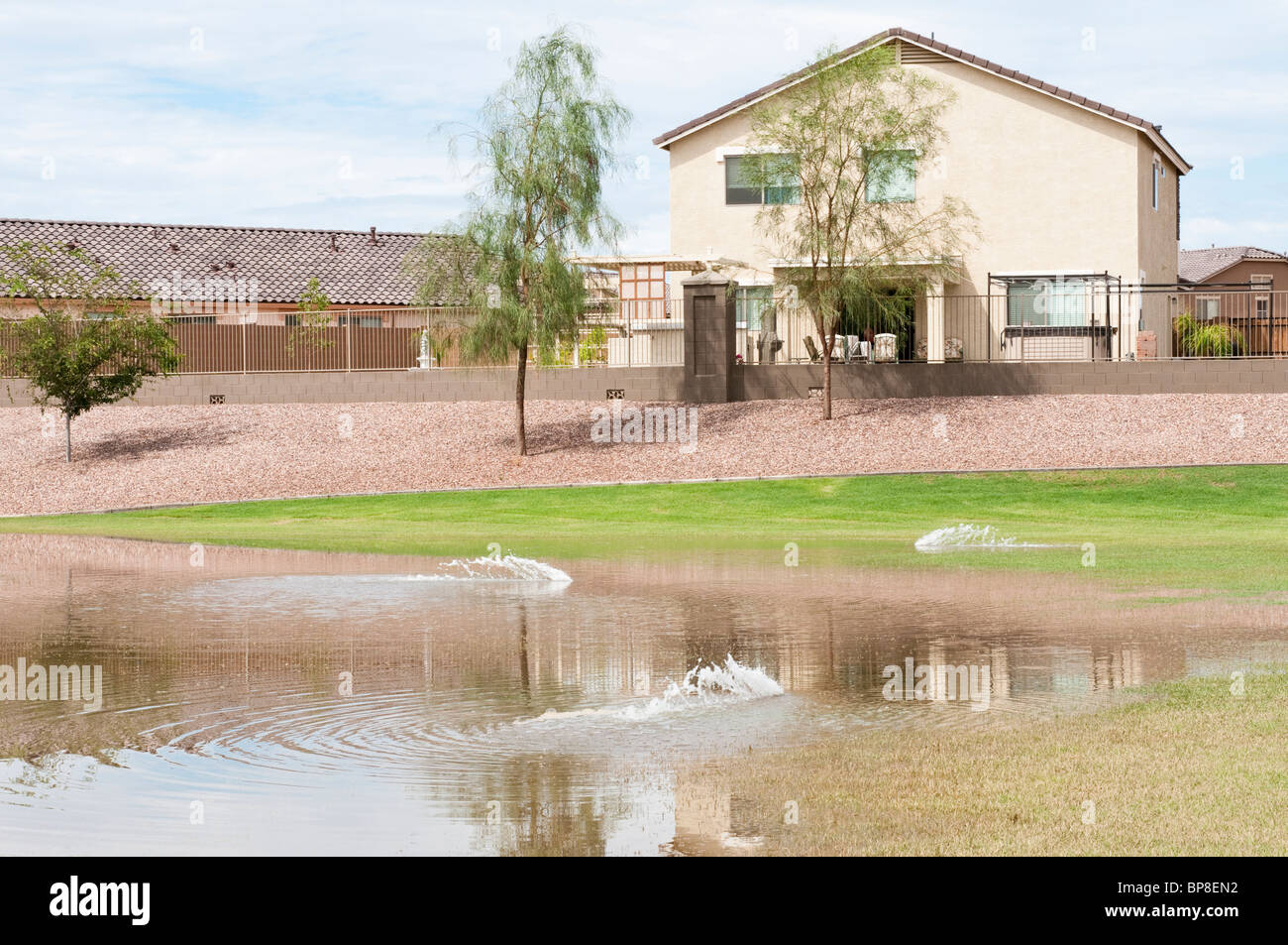 Un paesaggio automatico sistema di irrigazione spruzza acqua in un bacino dove acqua di temporale è stato raccolto dopo una pesante pioggia tempesta. Foto Stock