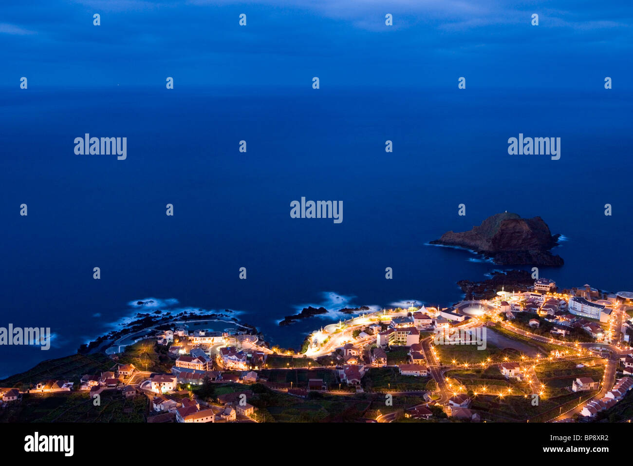 Città e piscine naturali di roccia visto da Miradouro da punto di vista Santinha al crepuscolo, Porto Moniz, Madeira, Portogallo Foto Stock
