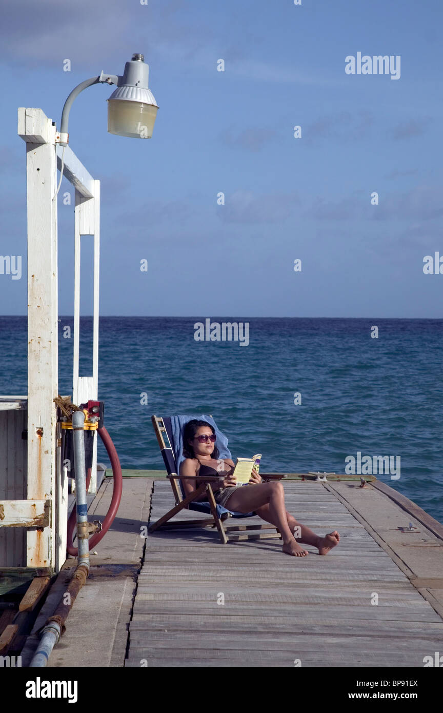 Donna rilassante sul molo, acque blu Inn, Bateau Bay, Speyside, Tobago, dei Caraibi Foto Stock