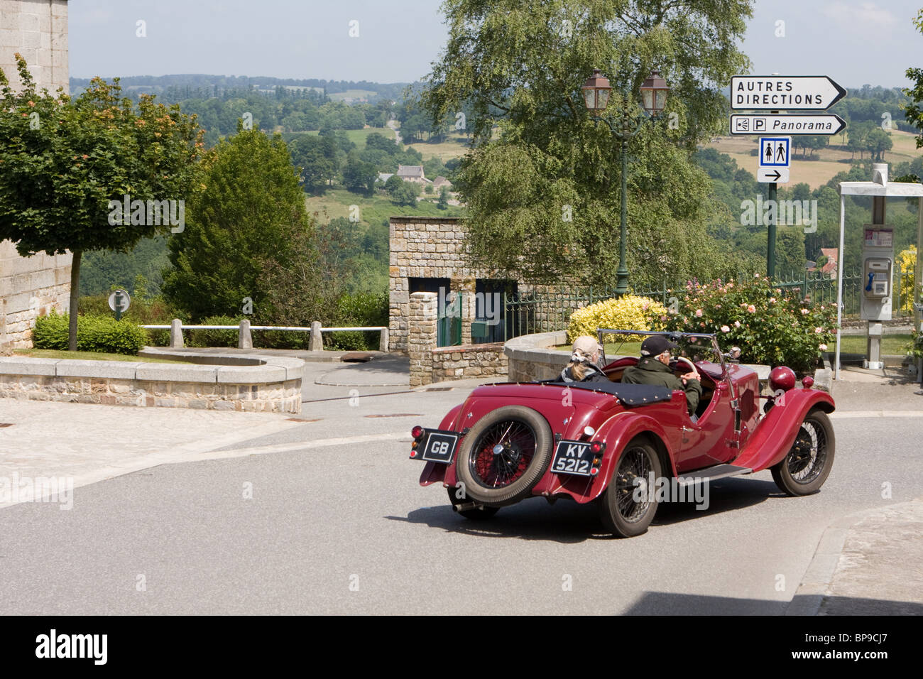 Classic British Riley motor car guida attraverso la città di Domfront in Francia con la parte superiore verso il basso Foto Stock