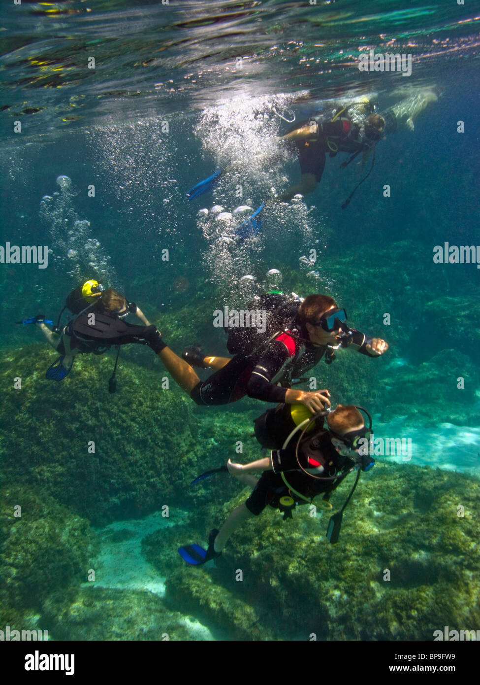 Un istruttore subacqueo è aiutare un bambino con la sua marcia sotto l'acqua. La laguna blu vicino a Cape Greco, Cipro, l'Europa. Foto Stock