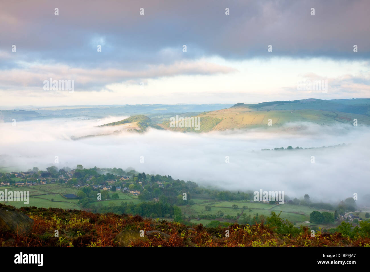 Una nebbiosa mattina di primavera visto dal bordo Curbar guardando sopra la nebbia riempito valle al di sopra del villaggio di Calver nel Derbyshire Foto Stock