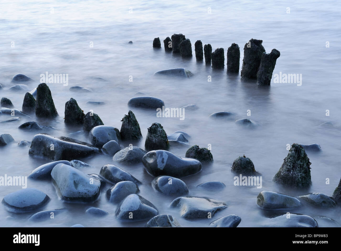 Un abstract di rocce e pennelli in legno sulla spiaggia Lilstock, Somerset. Una lenta velocità di otturatore causato l'acqua per sfocare pesantemente. Foto Stock