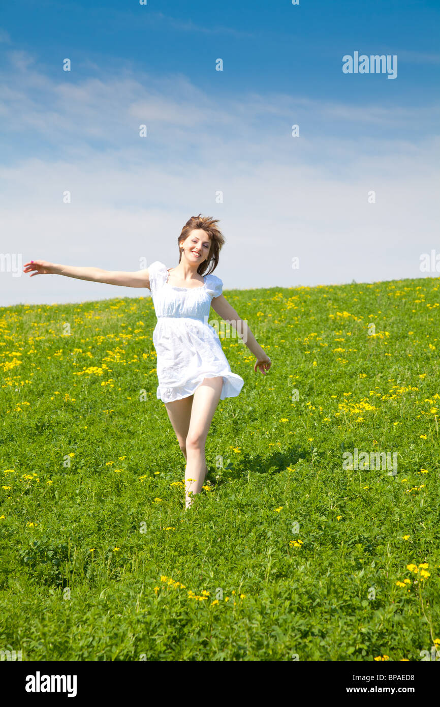 Giovane donna in esecuzione attraverso un campo di erba in primavera con colorate sciarpe Foto Stock