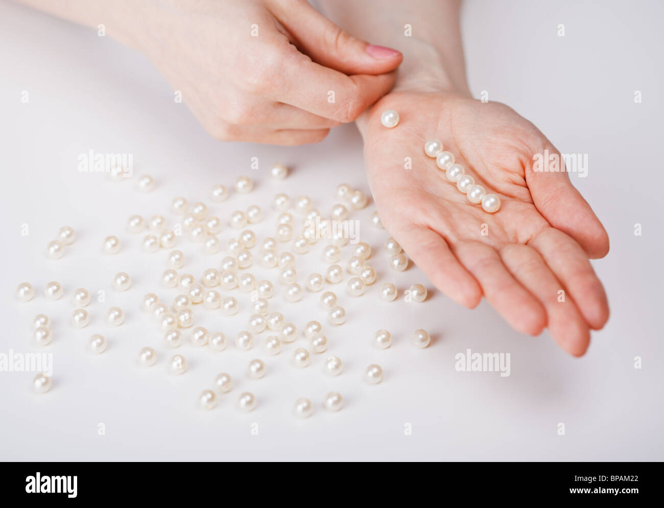 Mani femminili una raccolta di perle da perle di grandi dimensioni Foto Stock