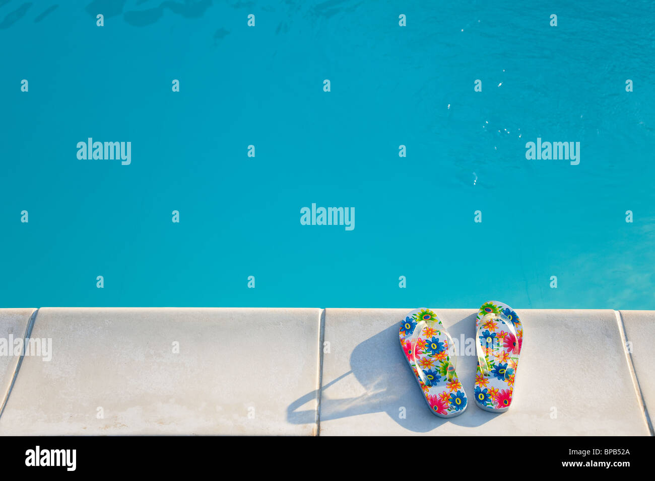 Il flip-flop vicino alla piscina nel sole al mattino Foto Stock
