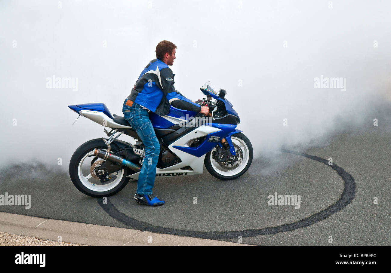 Motorcycllst su blu Suzuki GSX moto lasciando anello di gomma di pneumatici su strada - Francia. Foto Stock