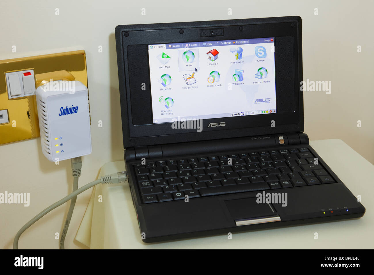 Netbook porta ethernet collegata al HomePlug nella presa elettrica per Internet a banda larga di andare online utilizzando il cablaggio elettrico Foto Stock
