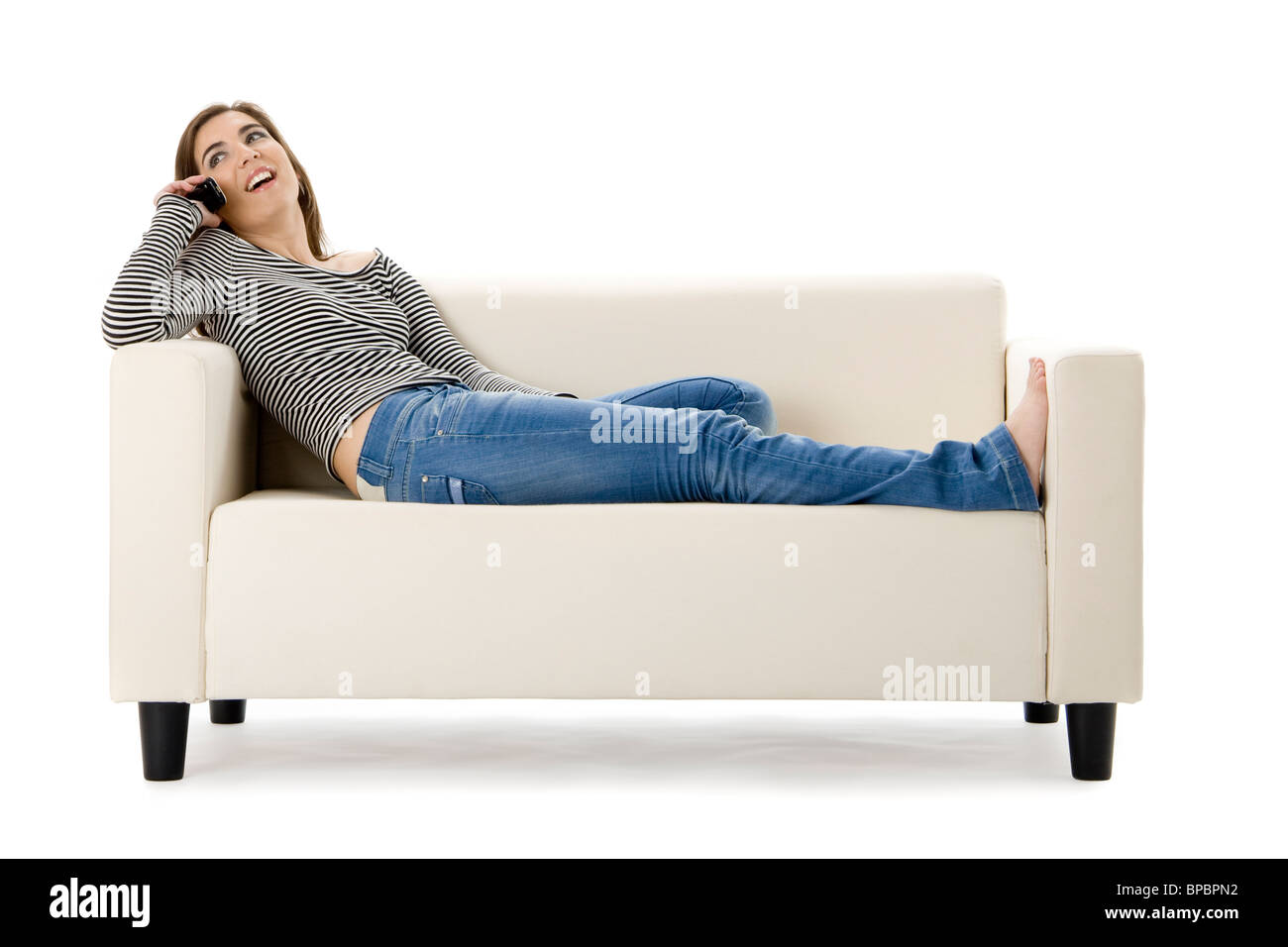 Bella donna felice su un divano bianco facendo una chiamata telefonica Foto Stock