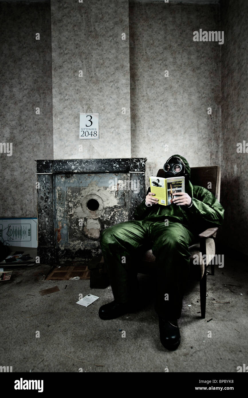 Un soldato che indossa la piena protezione ingranaggio e maschera a gas è occupato a leggere un libro, la vita nel 2048 Foto Stock