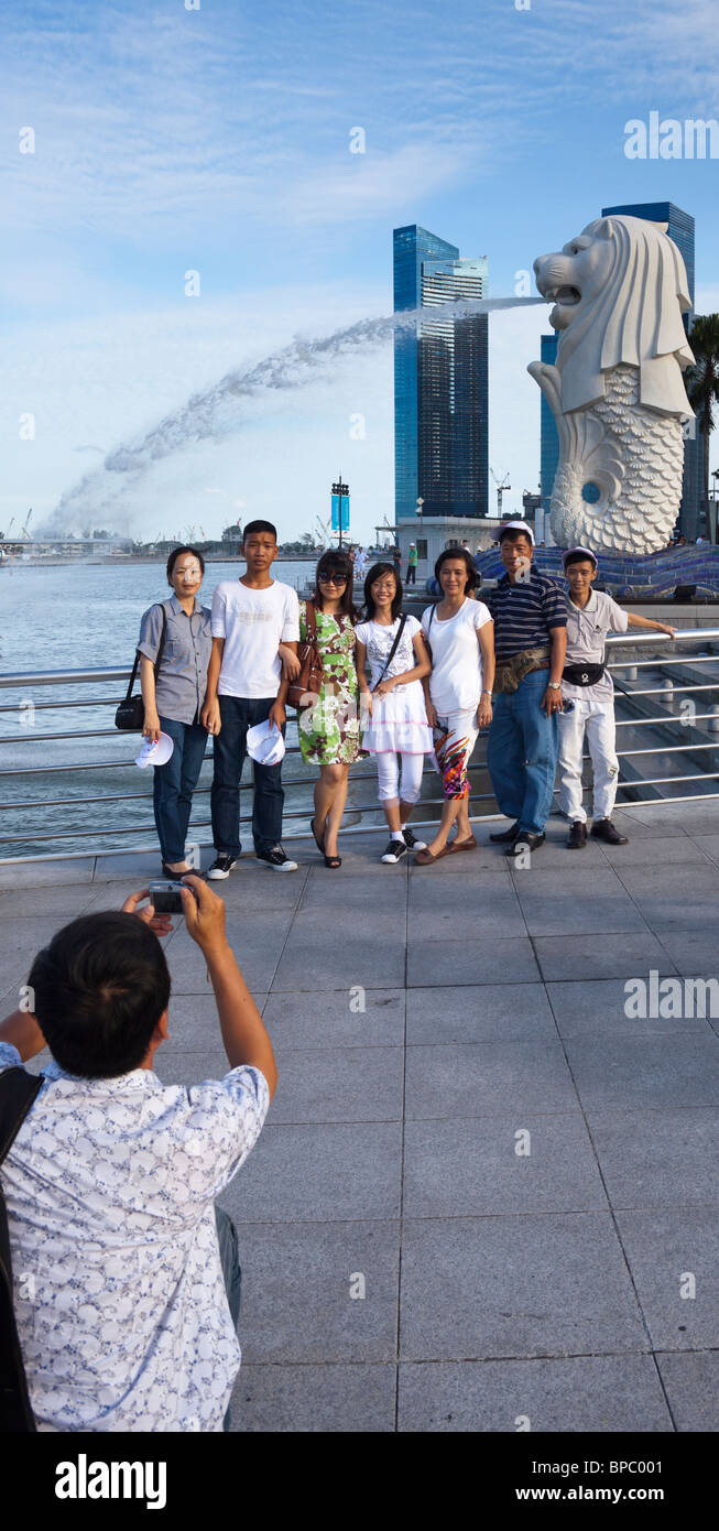 I turisti scattano fotografie di fronte al Merlion, il simbolo di Singapore Foto Stock