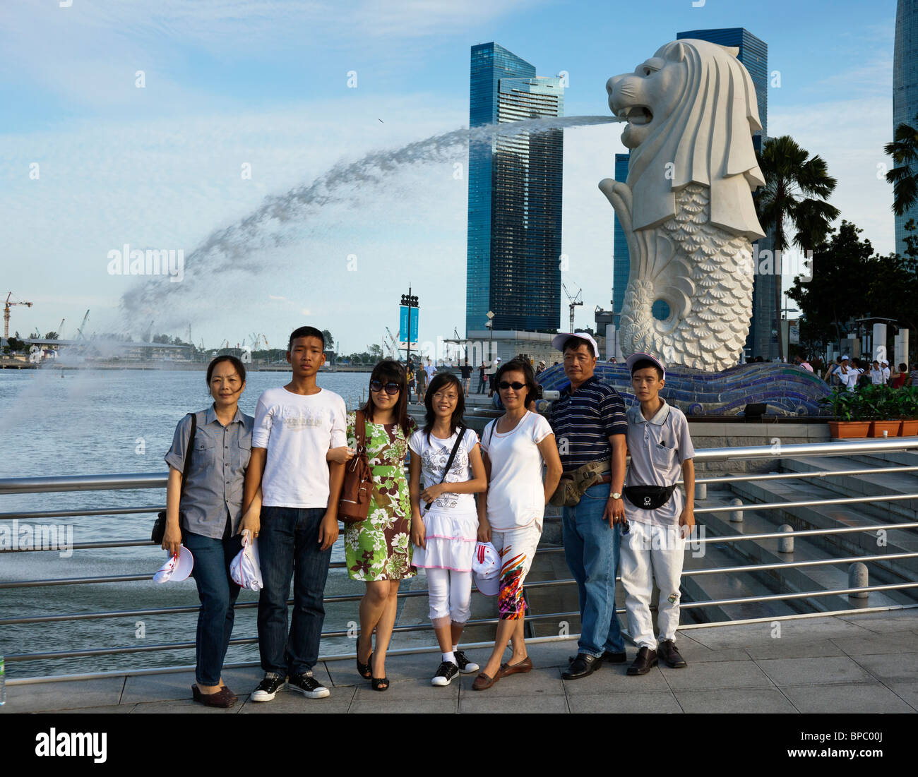 I turisti scattano fotografie di fronte al Merlion, il simbolo di Singapore Foto Stock