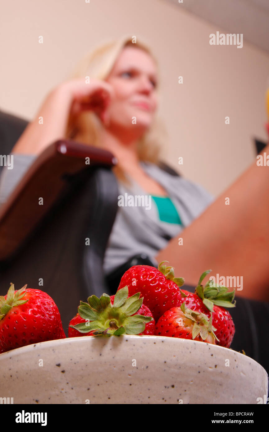 Coppa di fragole e una donna in un massaggio/sedia per pedicure Foto Stock