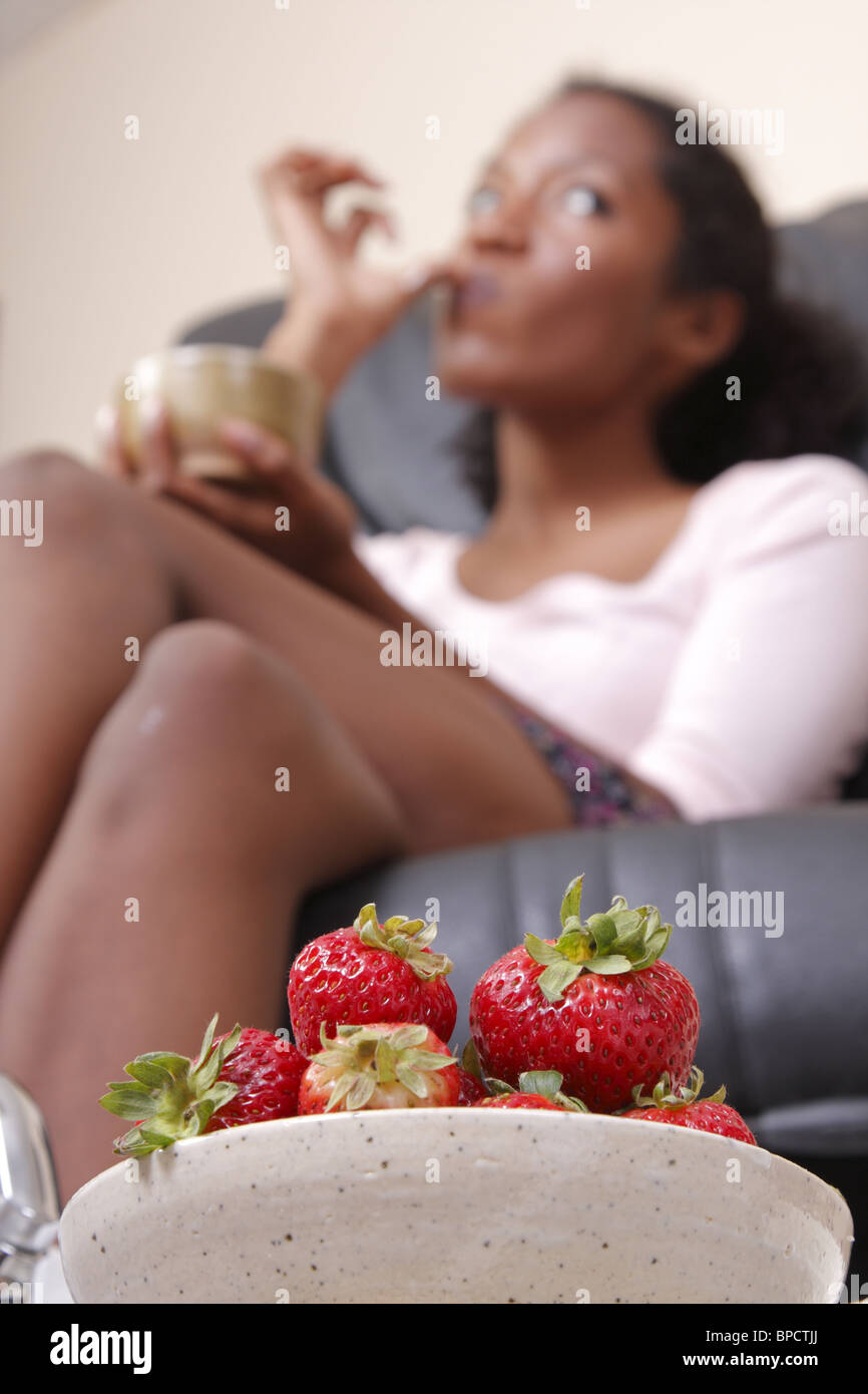 Una donna godendo le fragole ottenendo al contempo una pedicure Foto Stock