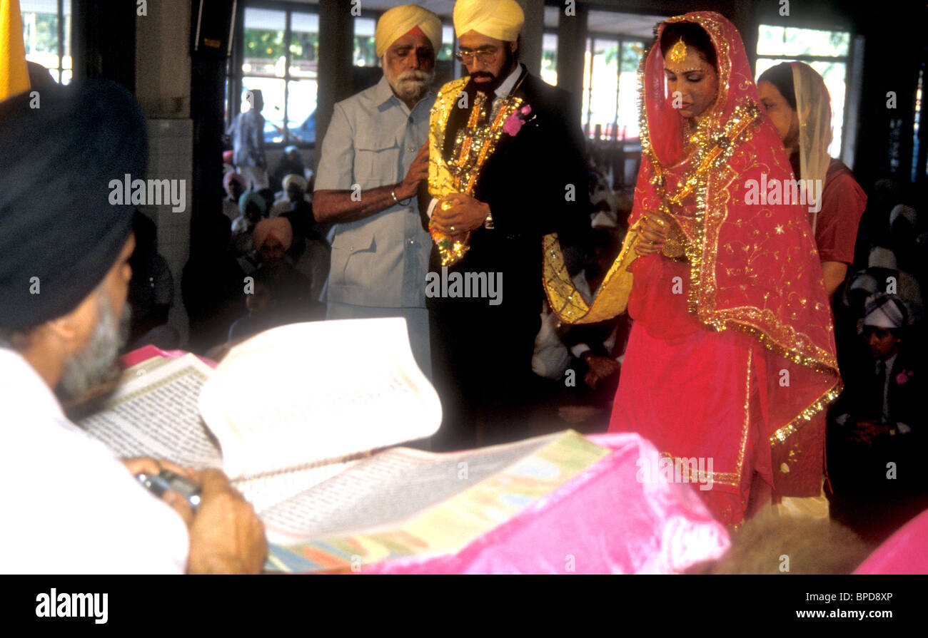 La religione sikh cerimonia di nozze nella gurdwara con il giovane in piedi nella parte anteriore del Guru Granth Sahib, Foto Stock
