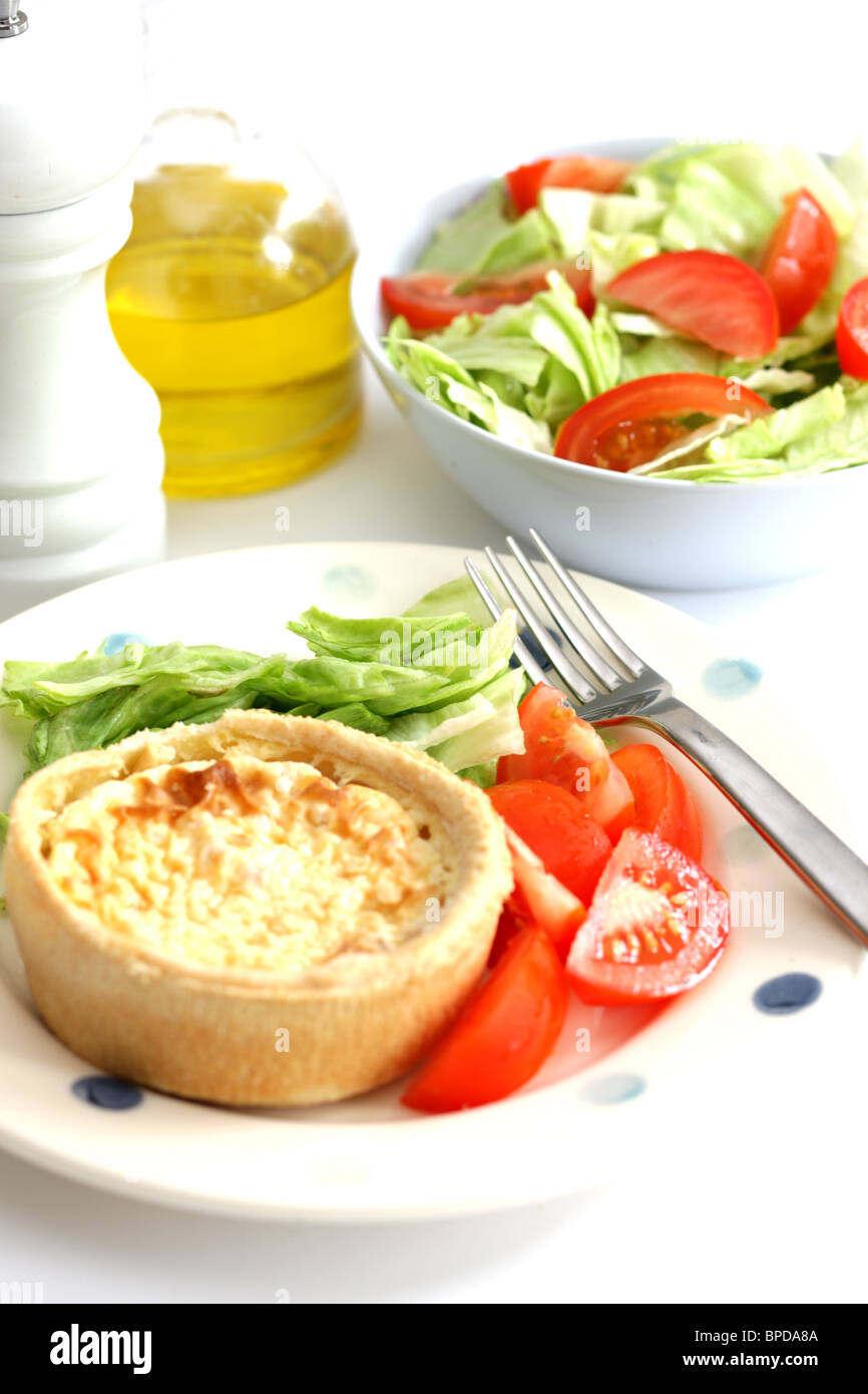 Pane appena sfornato Quiche Lorraine Flan individuali o crostata con un fresco e salutare mescolato giardino estivo con insalata di nessun popolo contro uno sfondo bianco Foto Stock