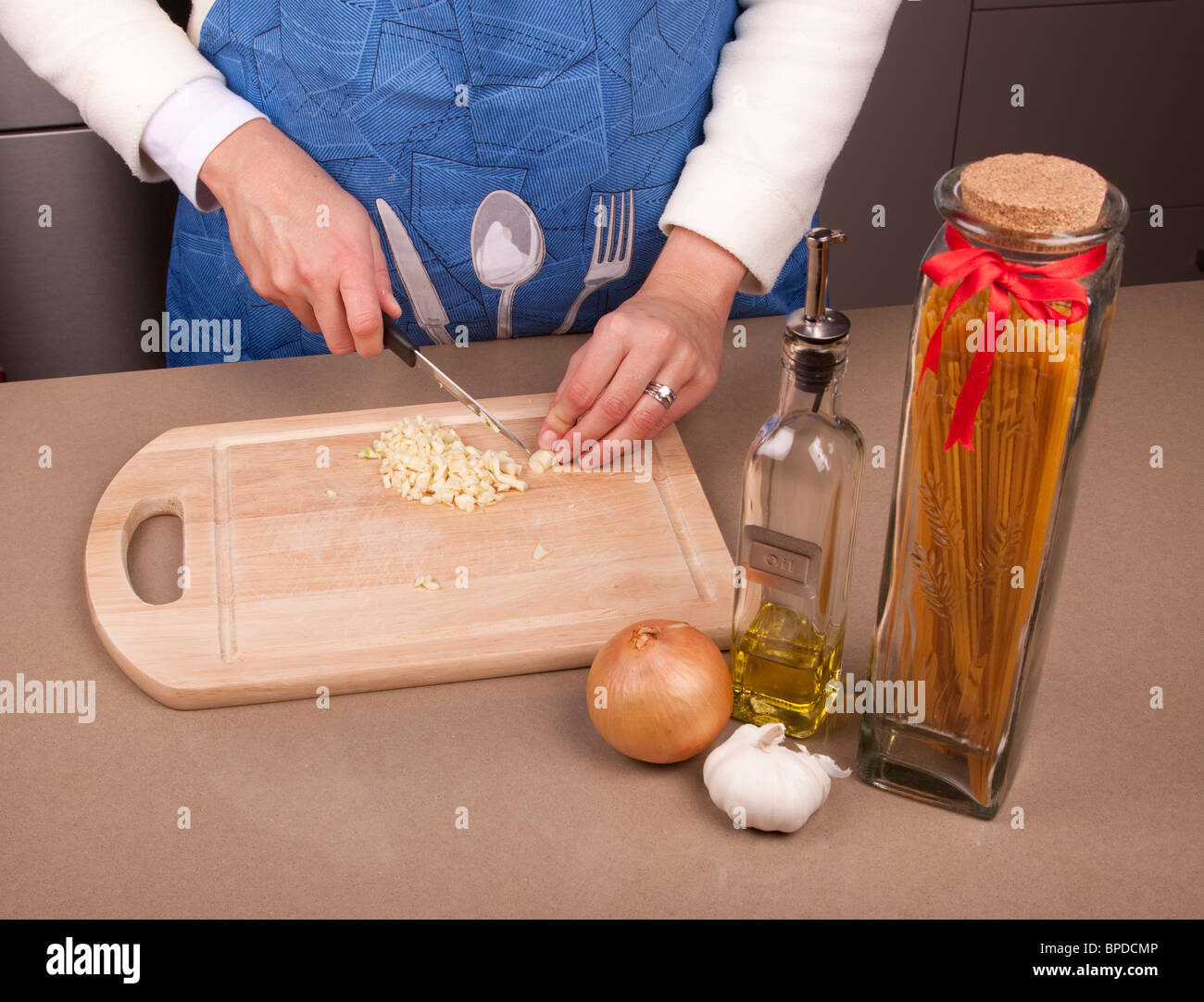 La donna il taglio di un po' d'aglio con olio e cipolla Foto Stock