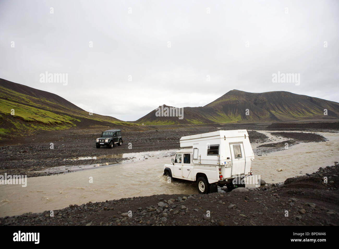 2 Land Rover guadato un fiume nelle Highlands interno dell'Islanda. Difensore 90 ed un difensore 130 con un camper Foto Stock