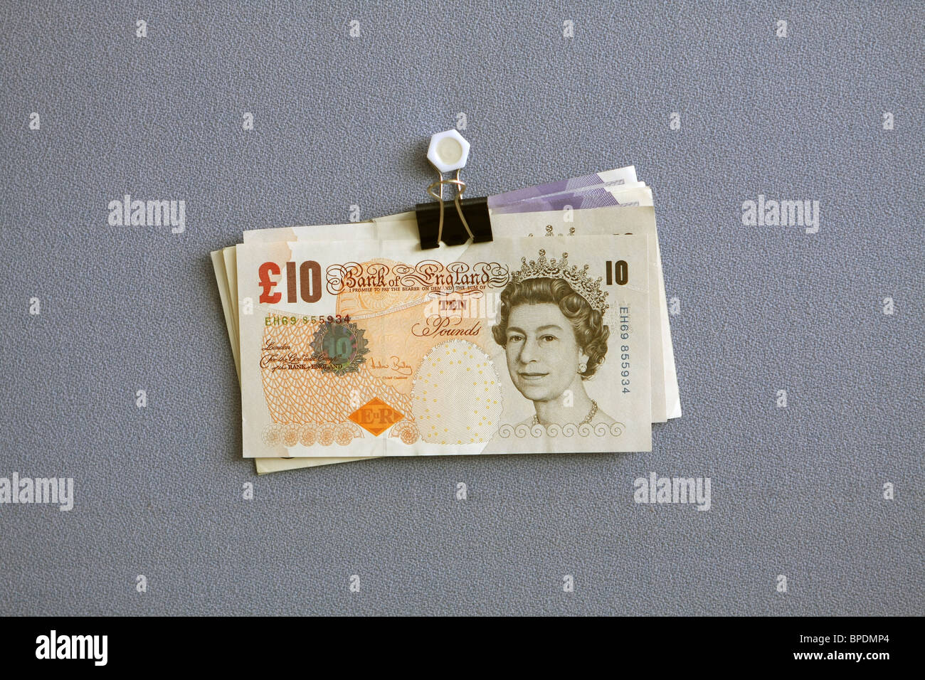 Sterling € 20 e € 10 note appeso un bulldog clip contro un panno blu sullo sfondo Foto Stock