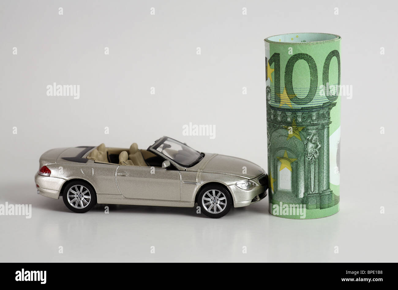 Un modello di auto e un rotolo di banconote in euro Foto Stock