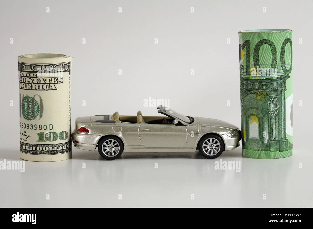 Un modello di auto tra i rotoli del dollaro e le banconote in euro Foto Stock