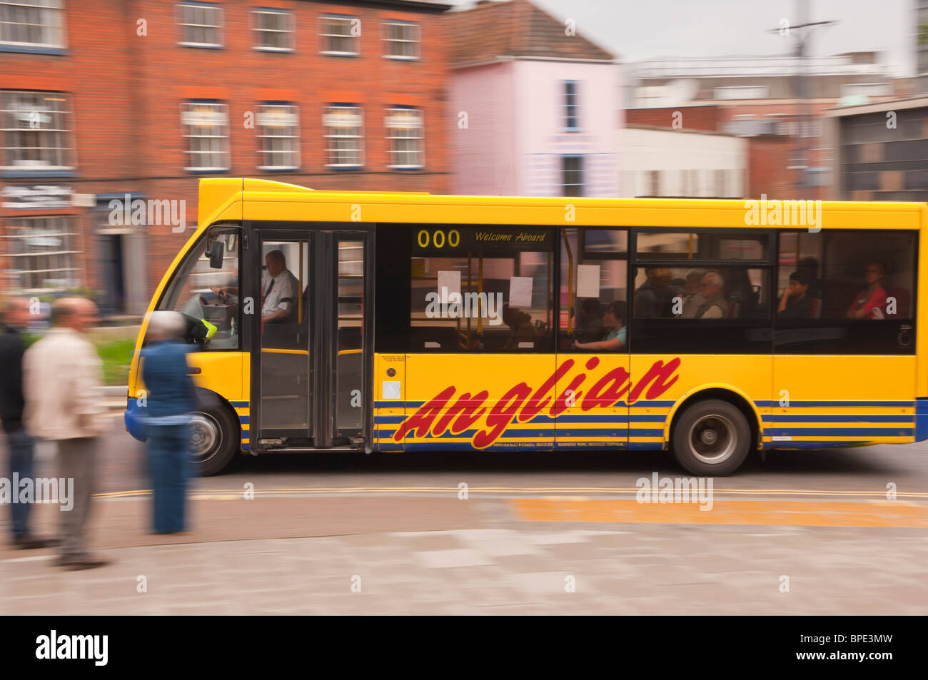 Un giallo Anglian bus granturismo guida attraverso la città che mostra il movimento in Norwich , Norfolk , in Inghilterra , Gran Bretagna , Regno Unito Foto Stock