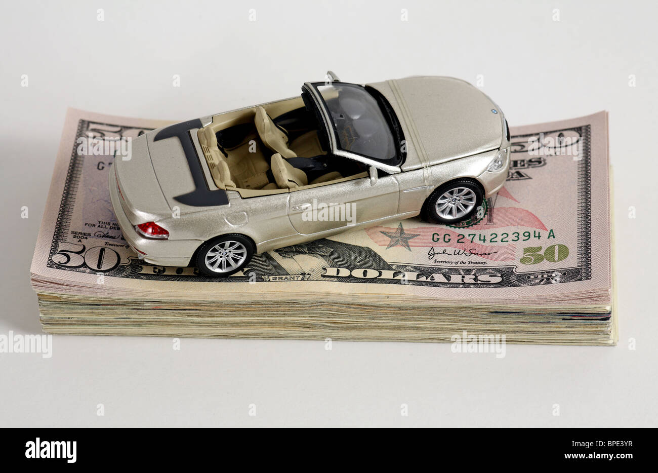 Un modello di auto su una pila di 50-dollaro banconote Foto Stock
