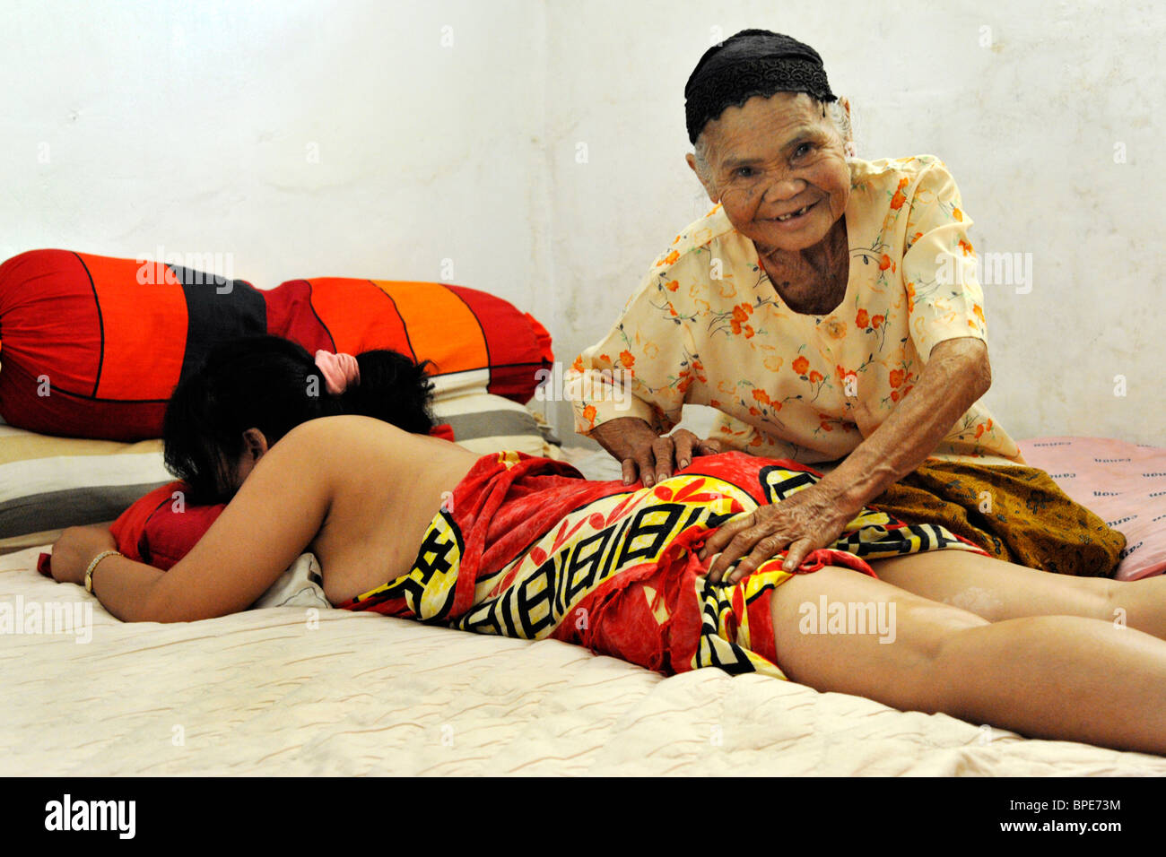 Old Lady dando giovane donna un massaggio tradizionale nella sua casa malang java indonesia Foto Stock