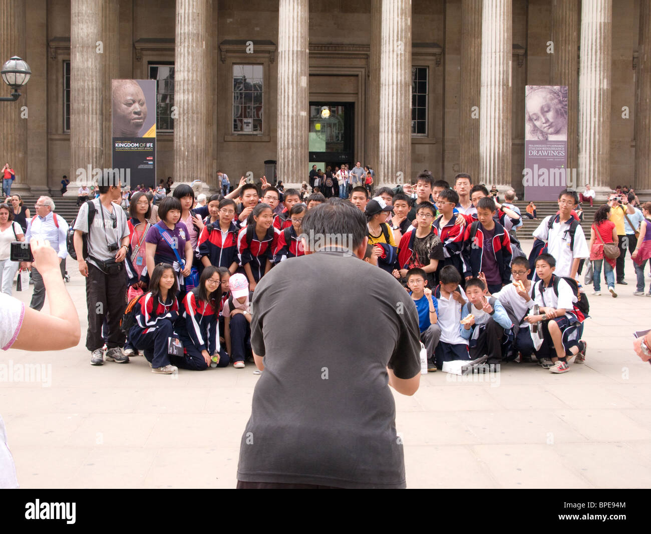 Un insegnante prende una fotografia della scuola straniera i bambini in gita scolastica al Museo Britannico Foto Stock