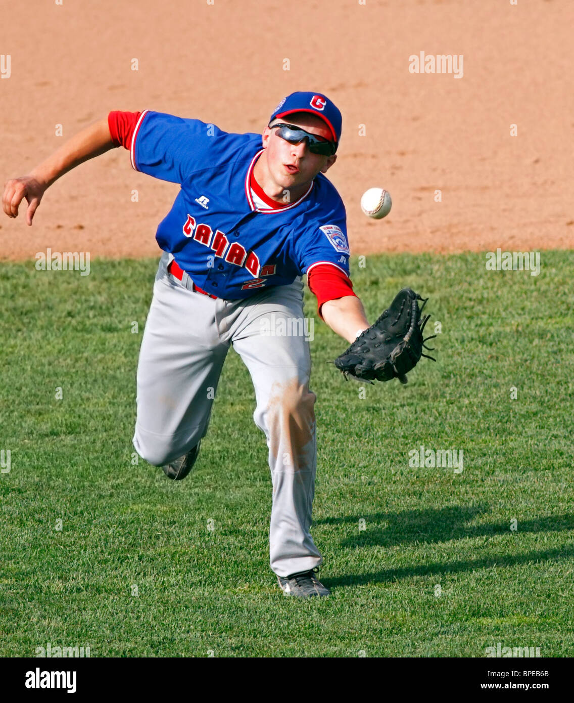 Terzo baseman Alex Cordingley del Canada addebita un rasoterra dalla distanza al 2010 Senior League Baseball World Series a Bangor, Maine. Foto Stock