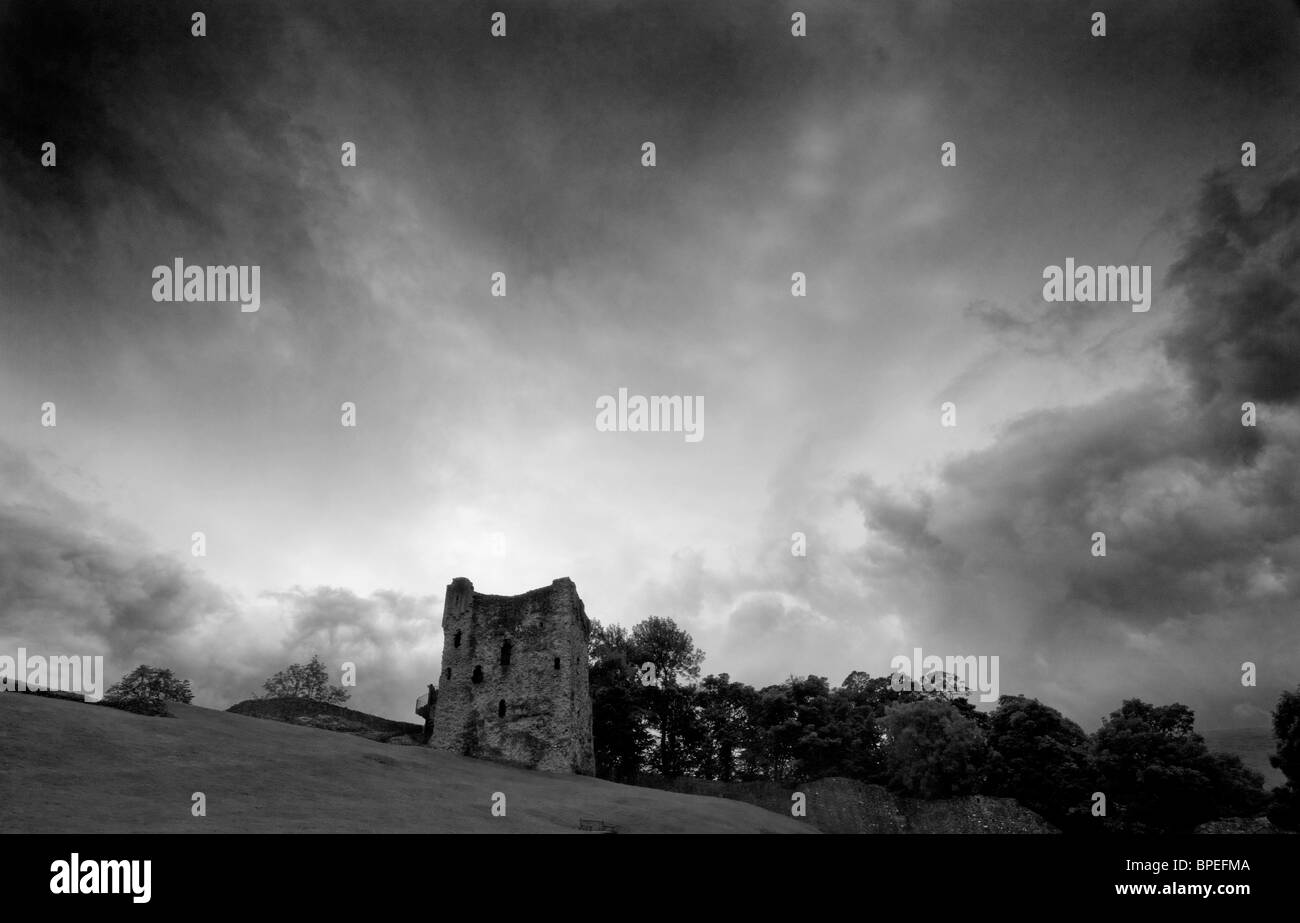 Una fotografia in bianco e nero alla ricerca fino al castello di Peverill nel Derbyshire. Ci sono alberi intorno al castello e un drammatico sky Foto Stock