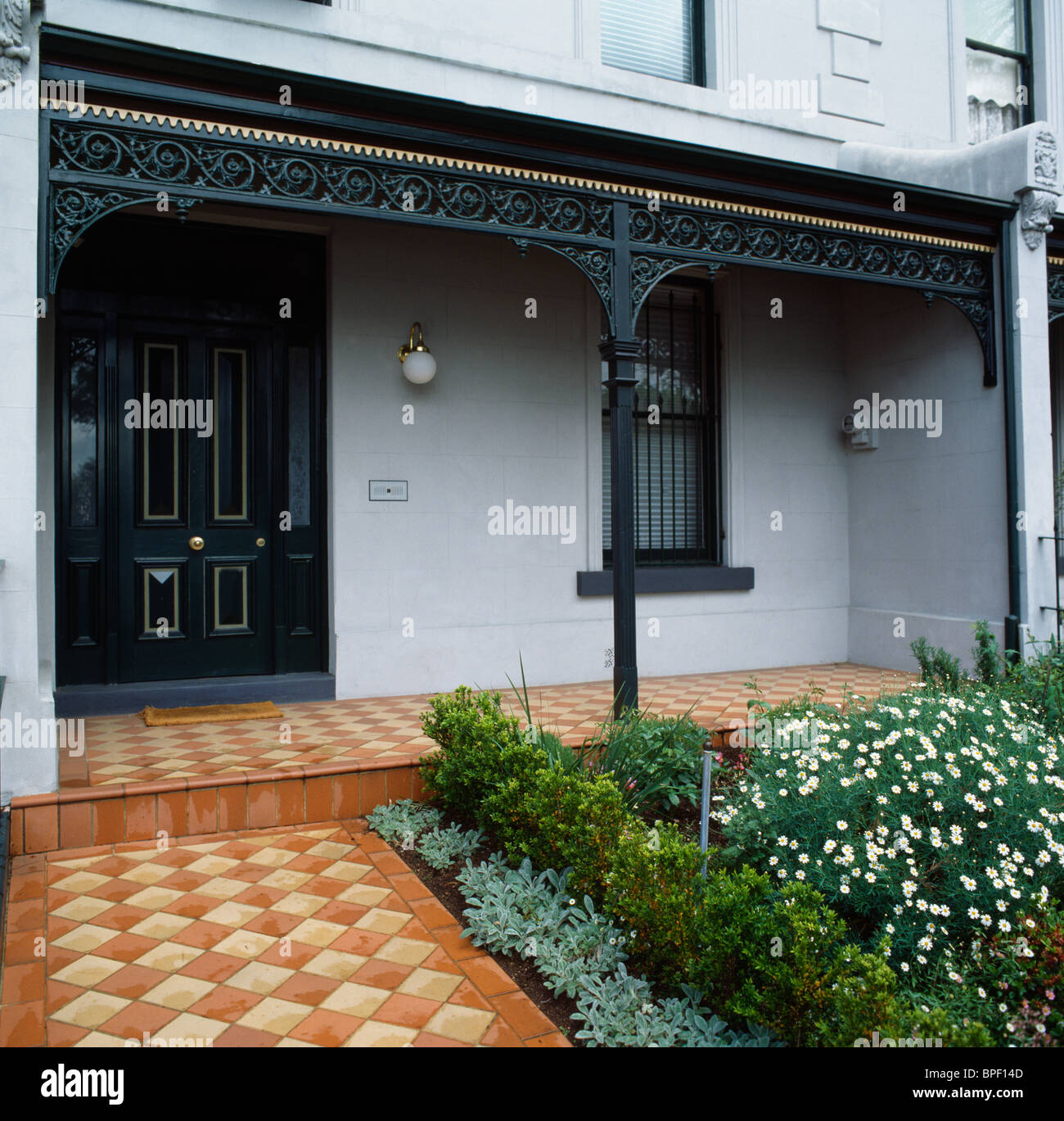 La terracotta checker board percorso piastrellato che conduce al nero porta anteriore e veranda della tradizionale australiana townhouse Foto Stock
