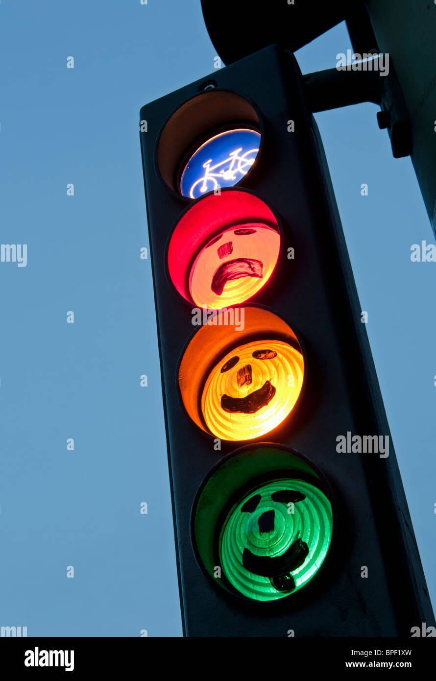 Facce disegnate sul ciclo di semafori al tramonto a Berlino Germania Foto Stock