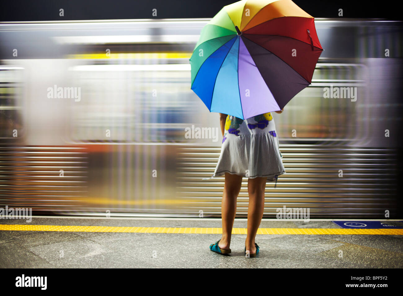 Razza mista donna con ombrello sulla piattaforma del treno Foto Stock