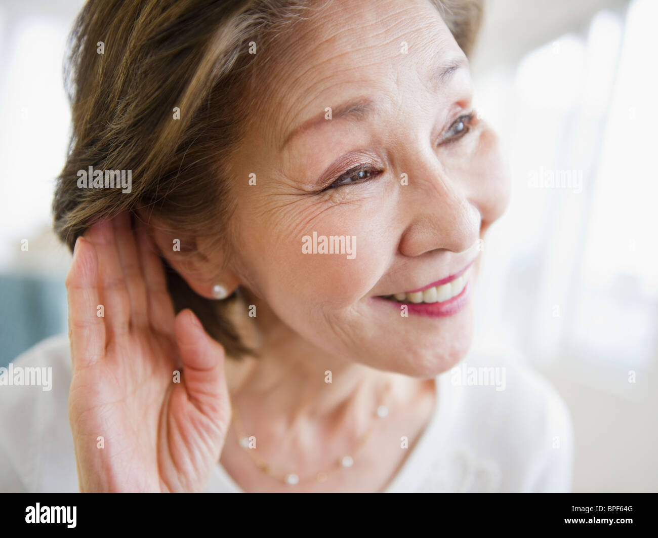 Donna Giapponese l ascolto con la mano vicino a orecchio Foto Stock