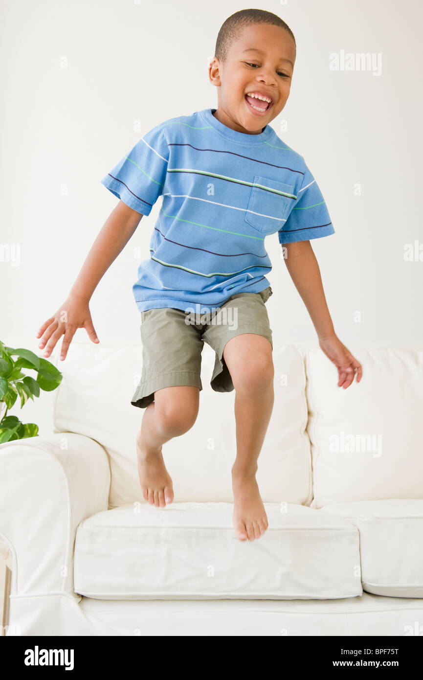 African American boy salta fuori divano Foto Stock