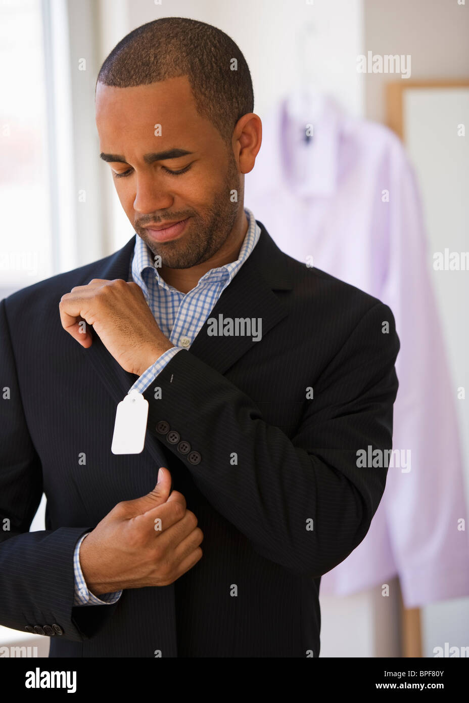 Razza mista shopper rendendo il viso a prezzo di etichetta sulla camicia Foto Stock